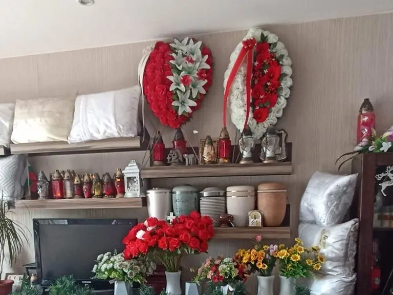 Траурни венци, кандила, урни и цветя, подредени на рафтове